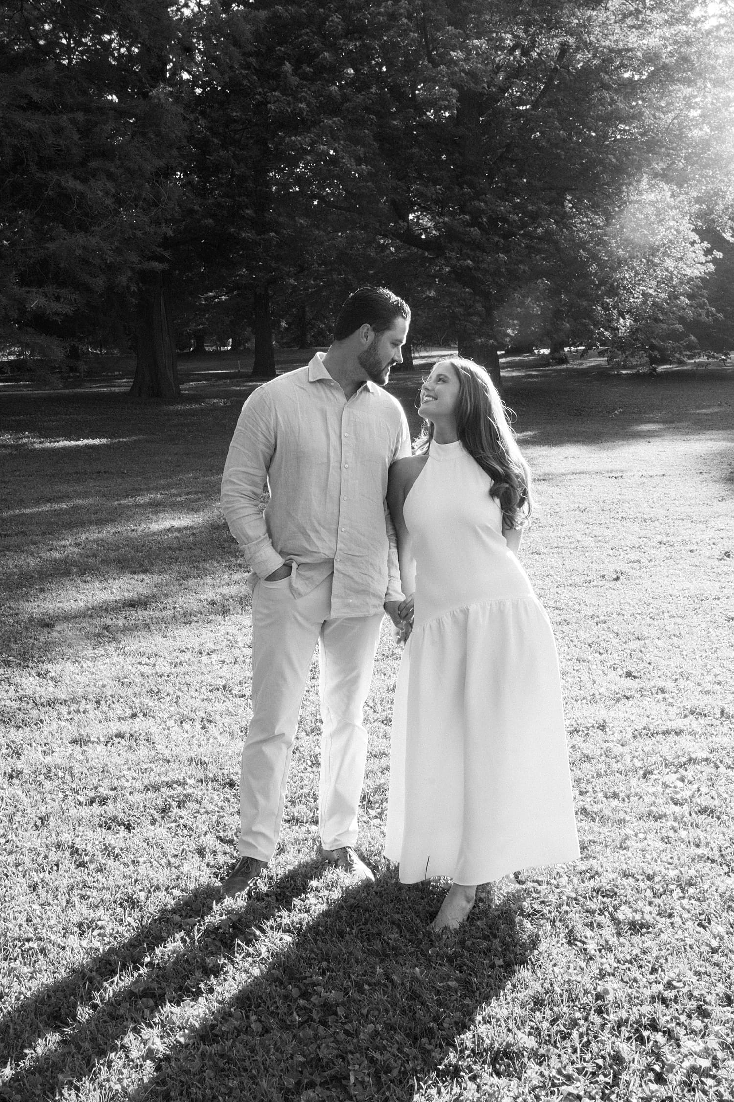 couple walk hand in hand through field by documentary wedding photographer