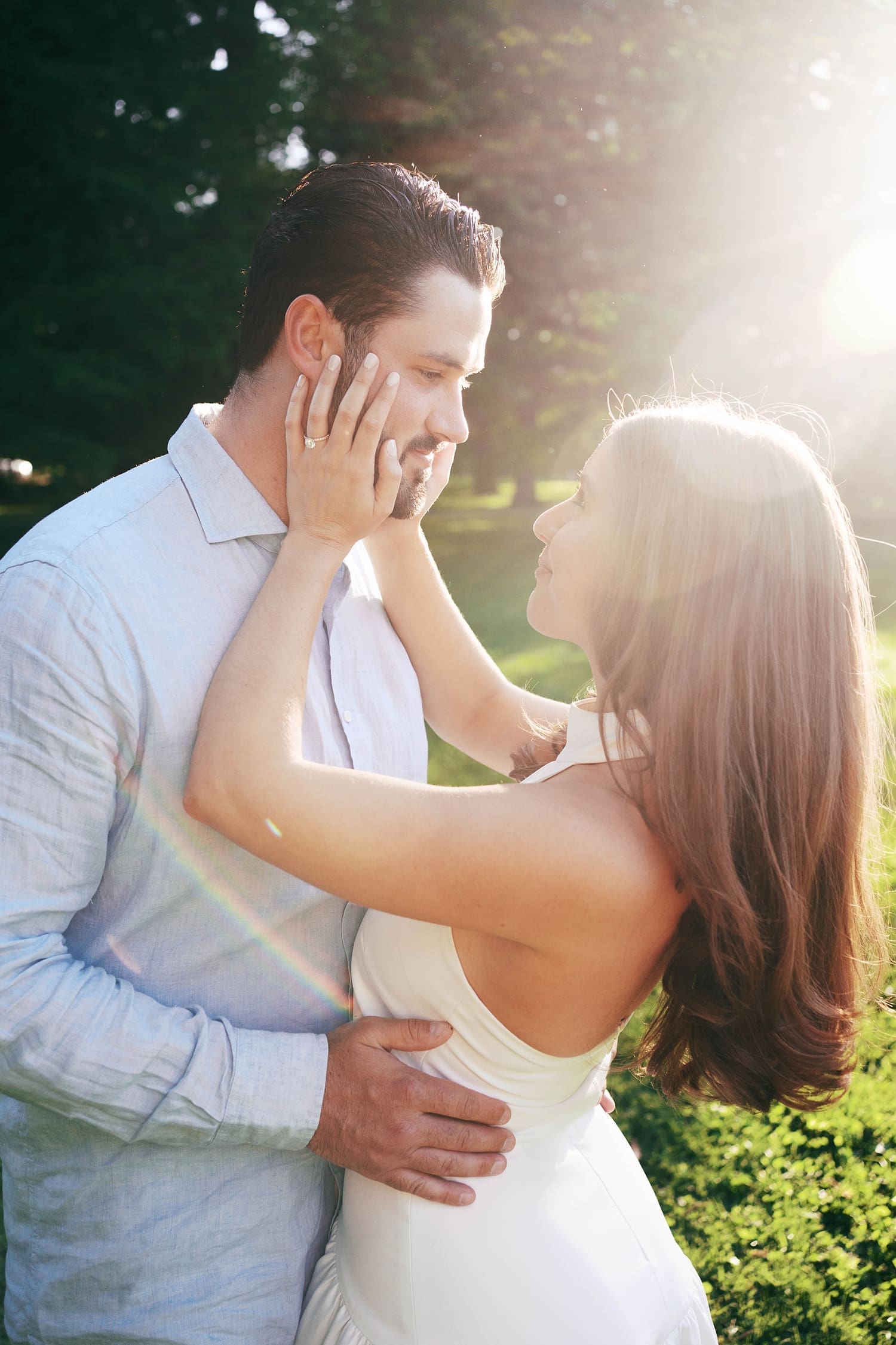brunette bride in white dress holds her fiancé's face by documentary wedding photographer