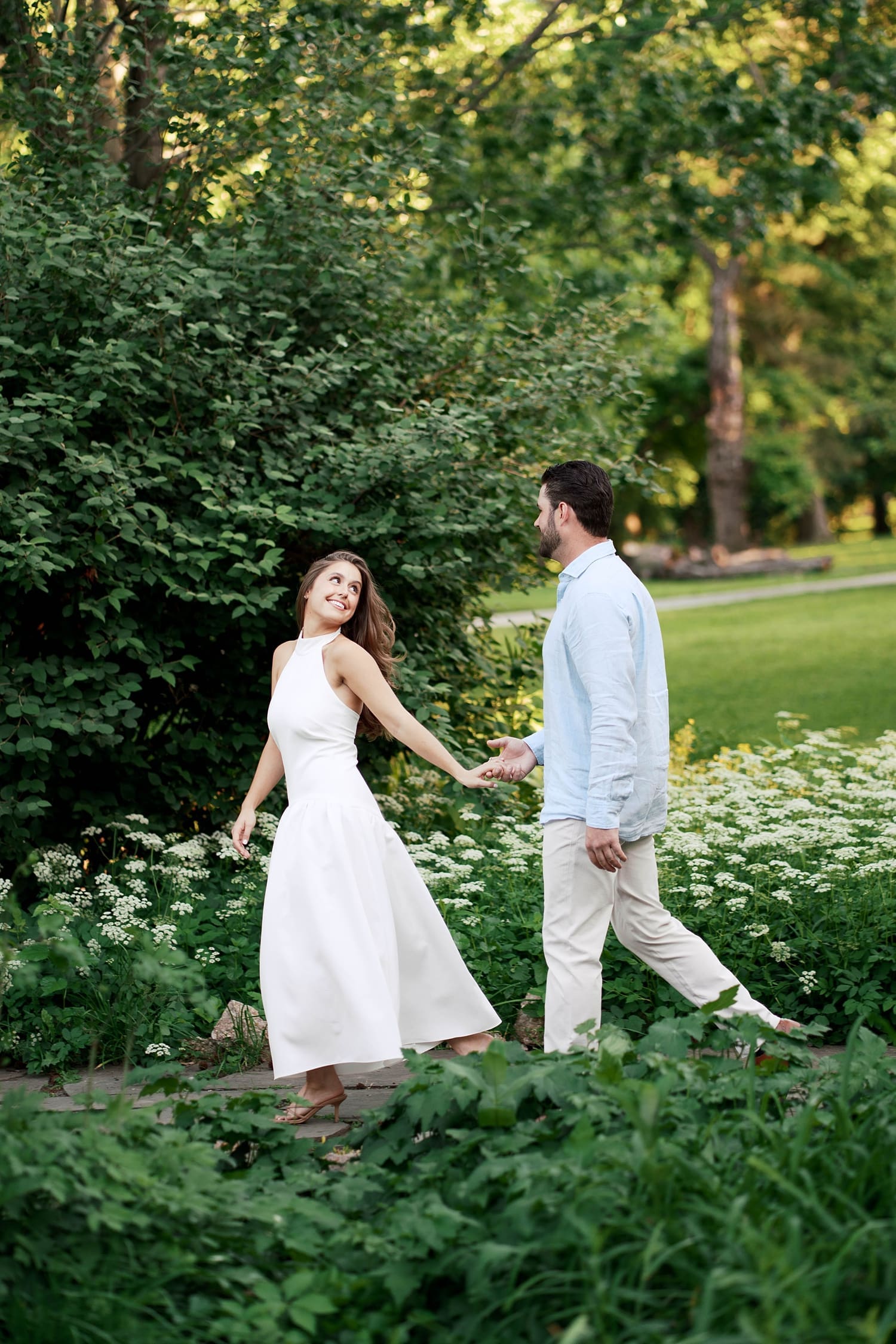 woman leads man through flower garden in park by Camille Meers Photography