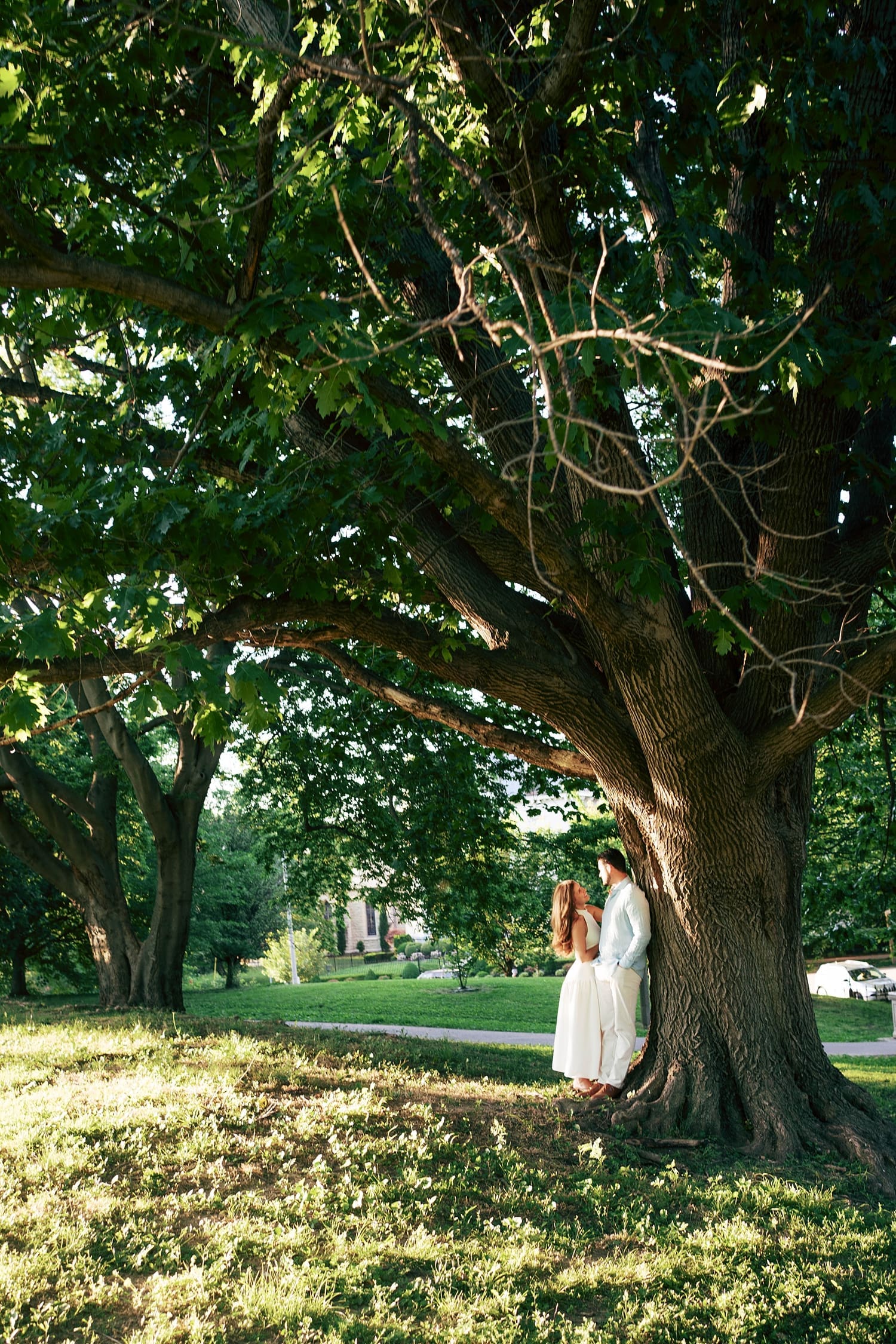 couple stand under a large oak tree for unposed engagement session