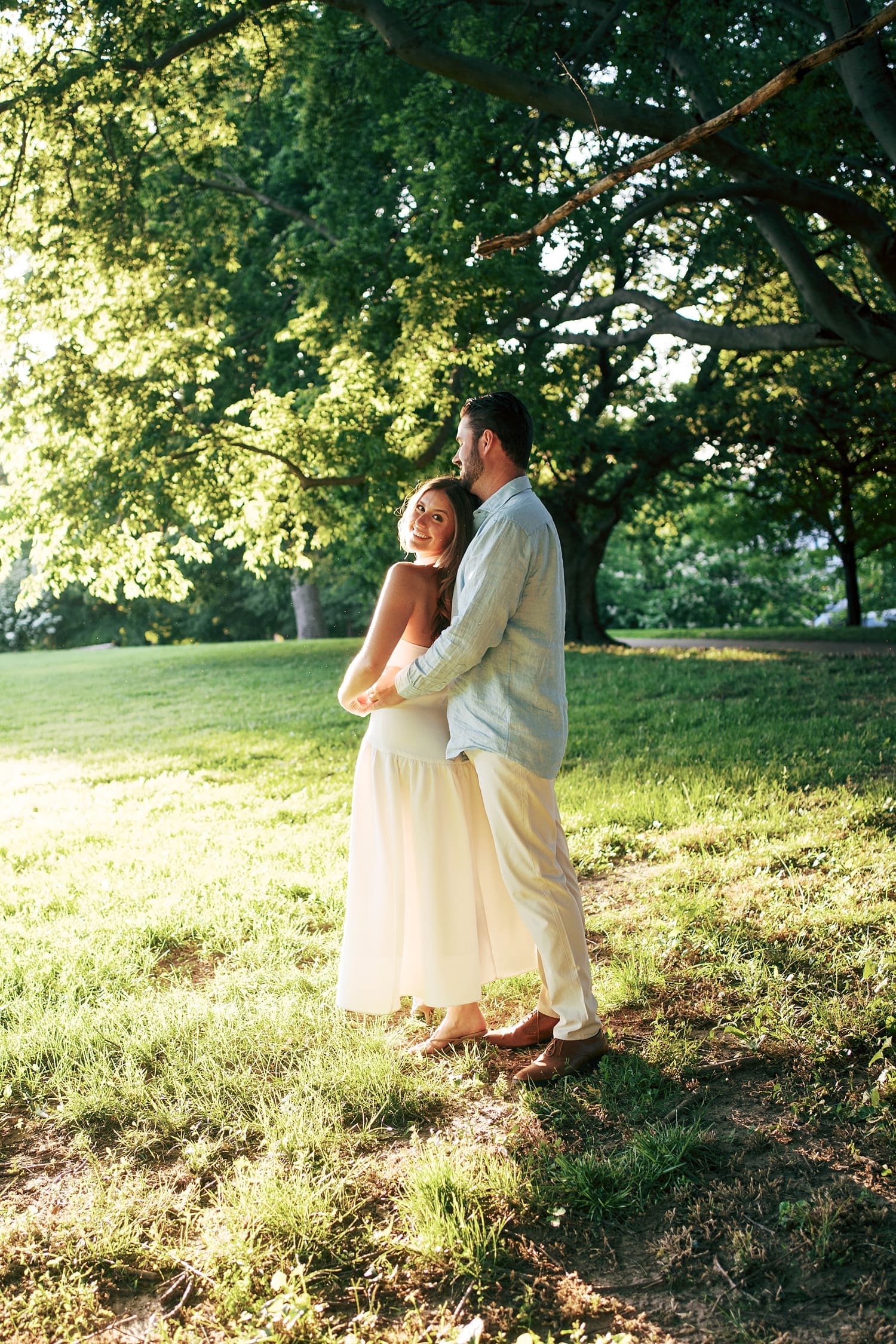 man wraps up his fiancé in embrace under tree by Camille Meers Photography