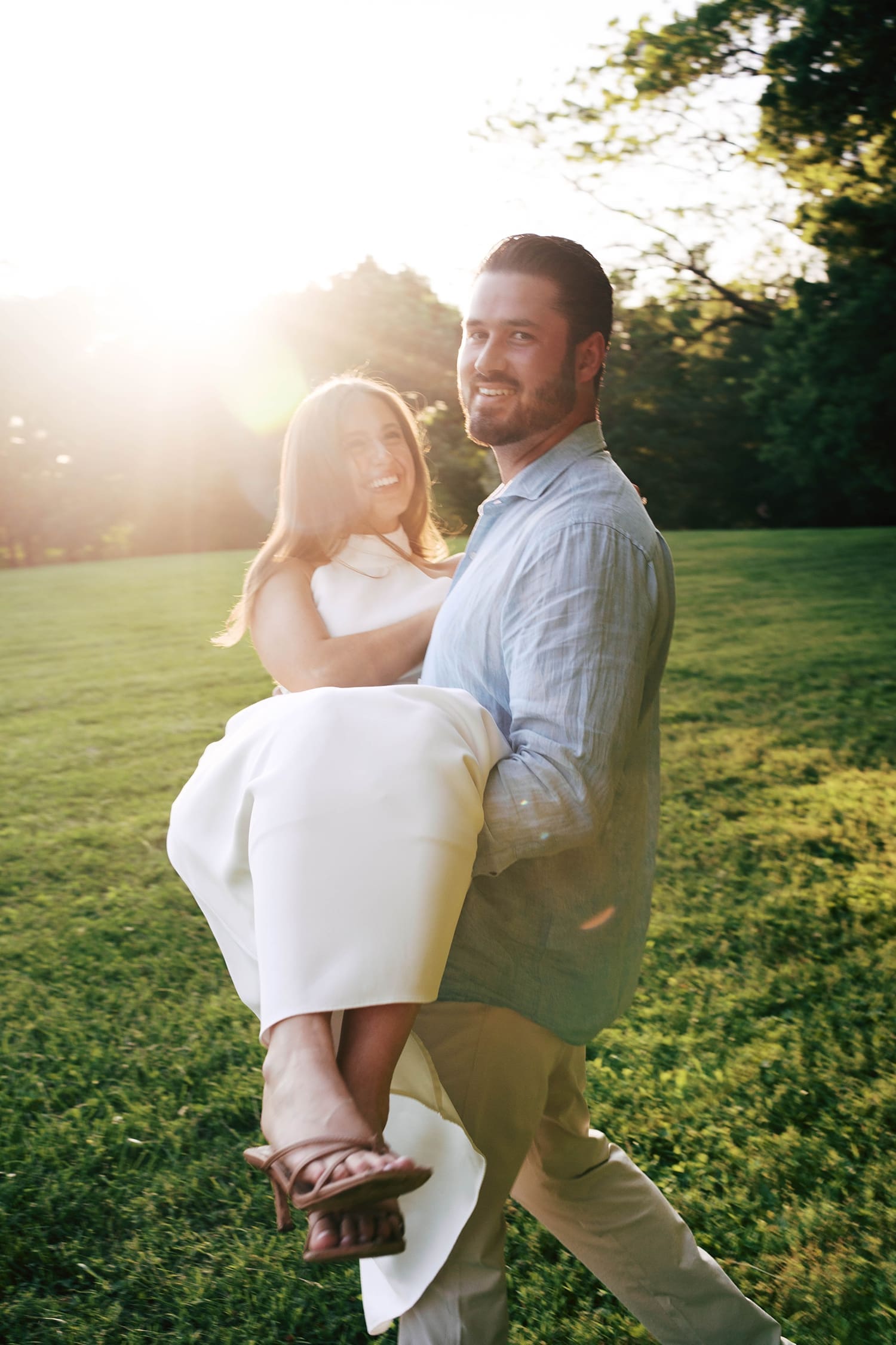 groom to be spins his fiance in golden hour lighting by documentary wedding photographer