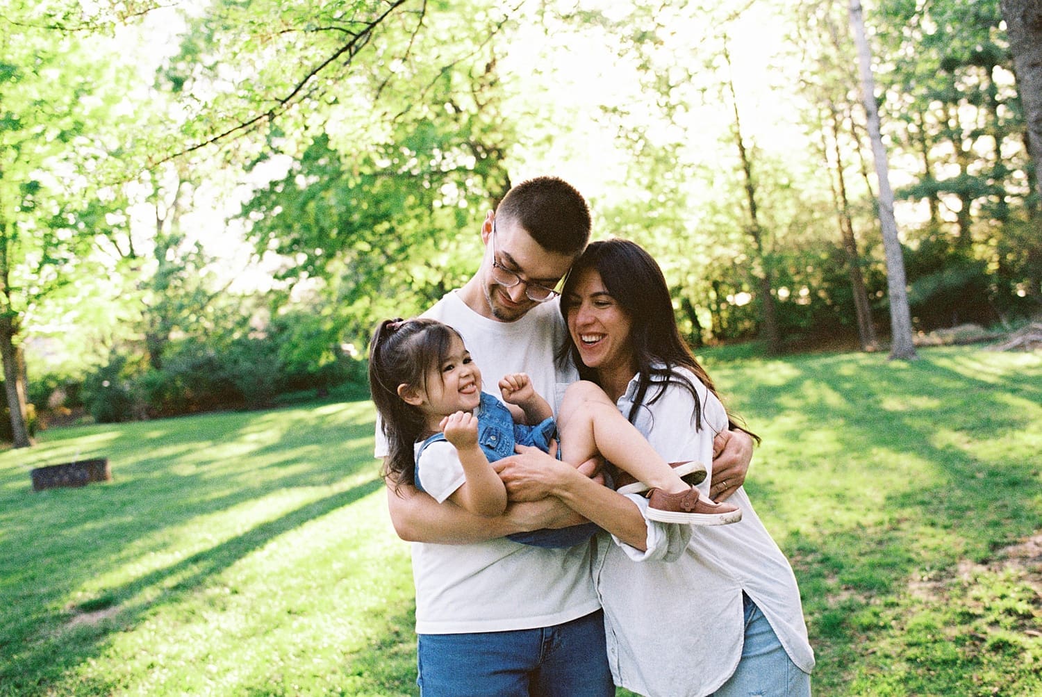 parents hold and tickle their laughing toddler by Camille Meers Photography