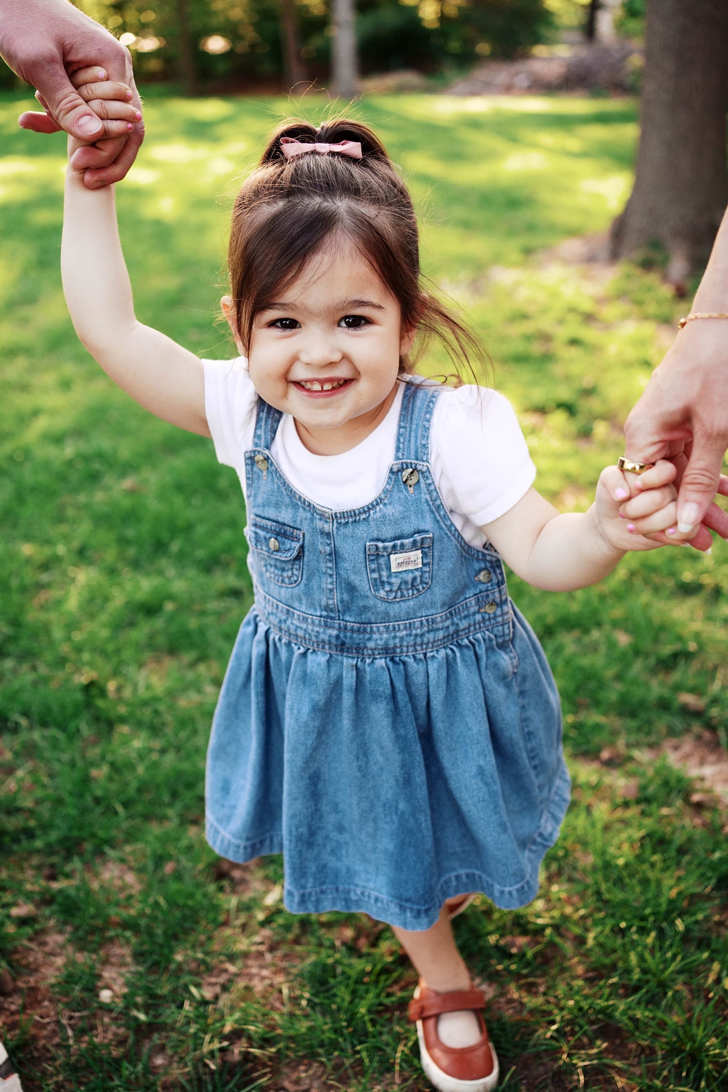 toddler holds her parents hands for candid maternity photo session