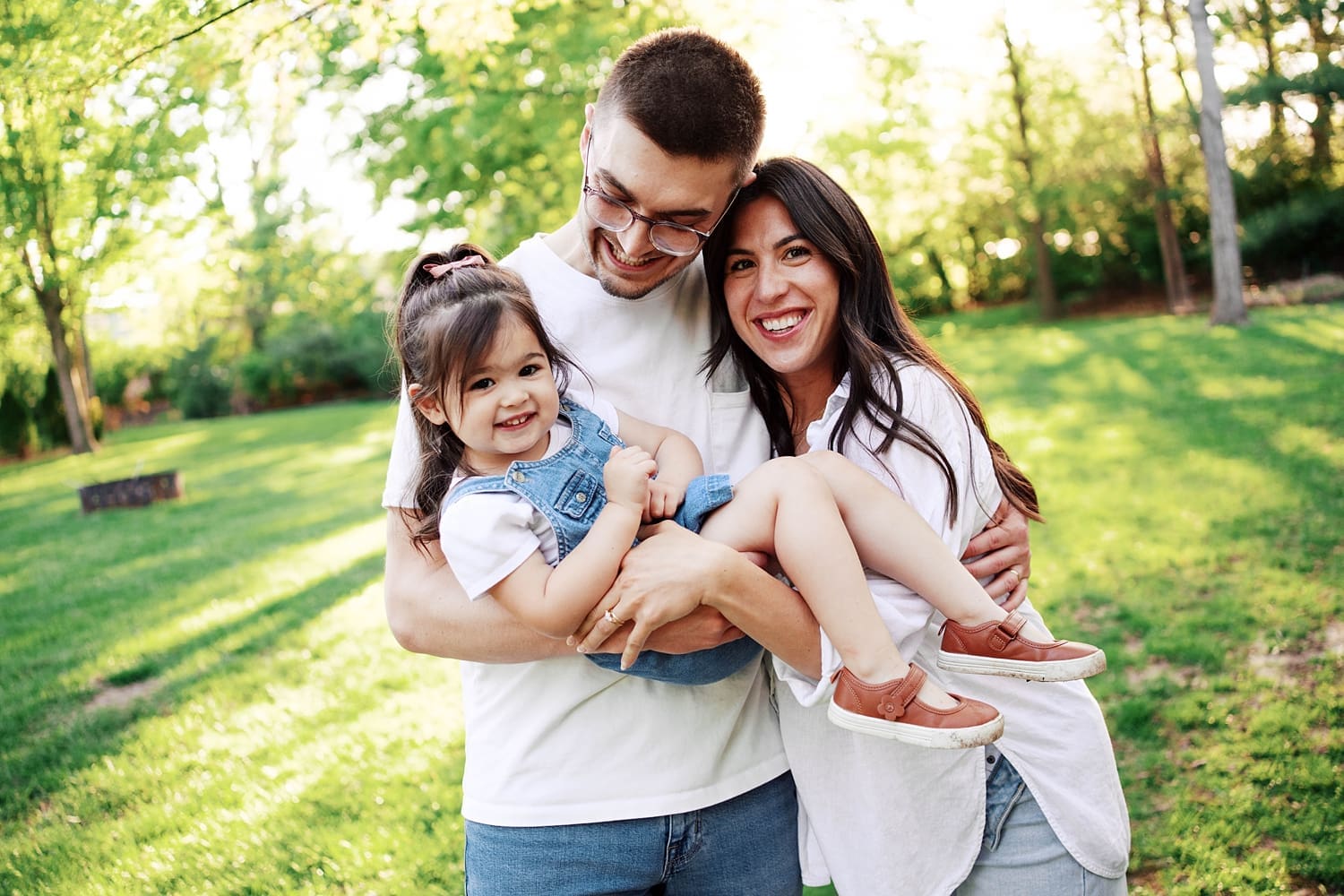 family of three snuggles in backyard for candid maternity photo session