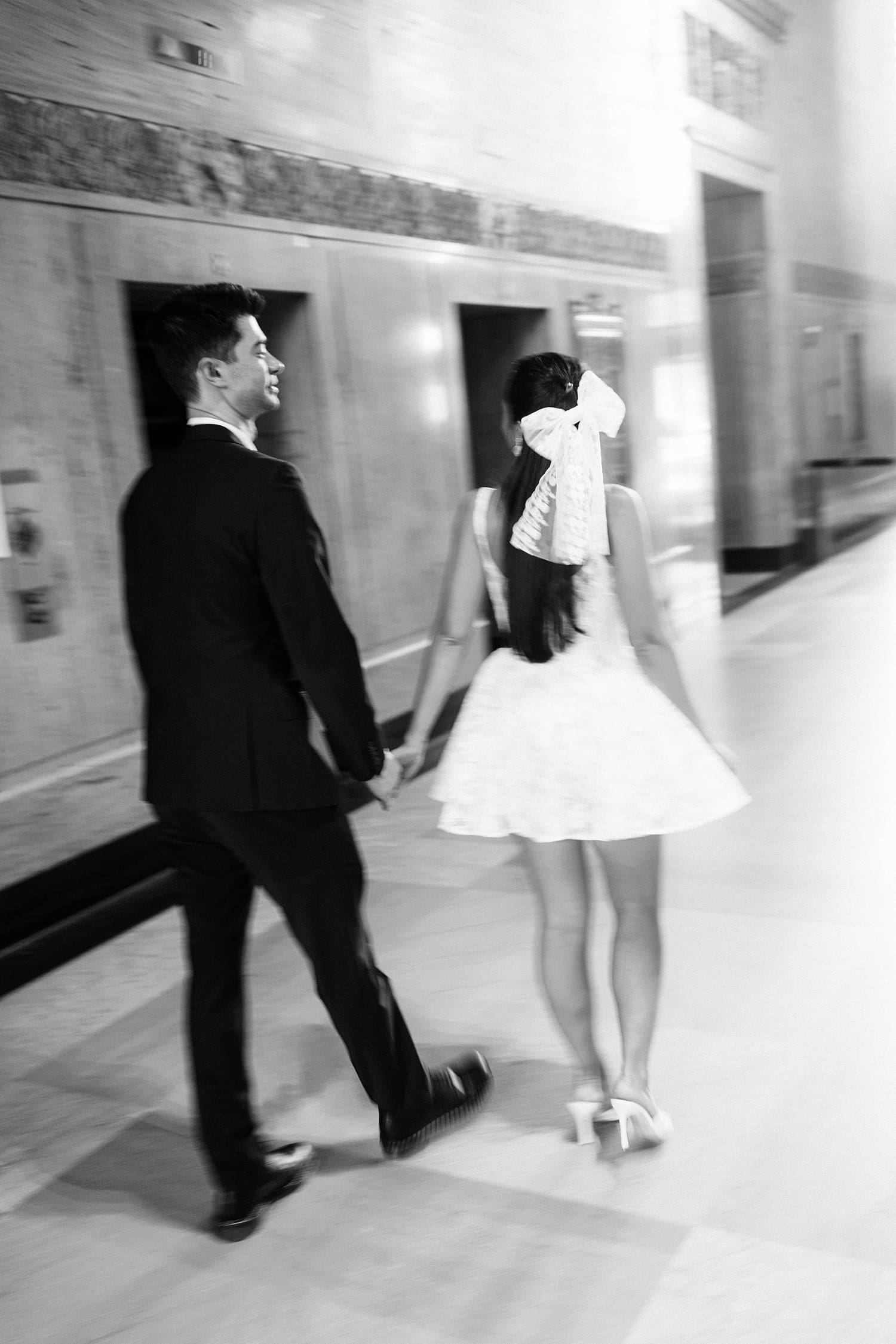 bride with big bow in hair walks down corridor with husband by Missouri elopement photographer