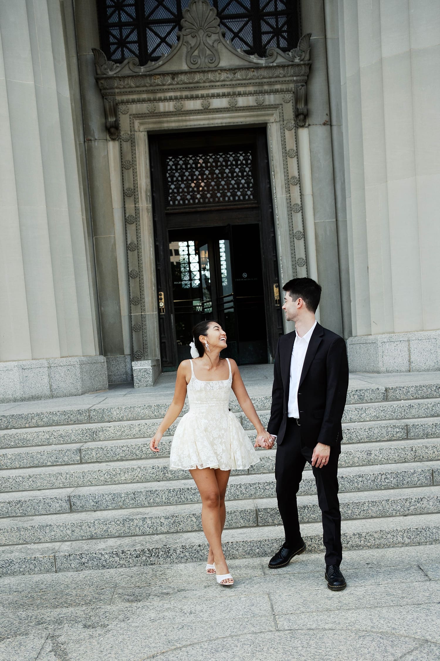newlyweds walk hand in hand down the steps at the St. Louis Courthouse