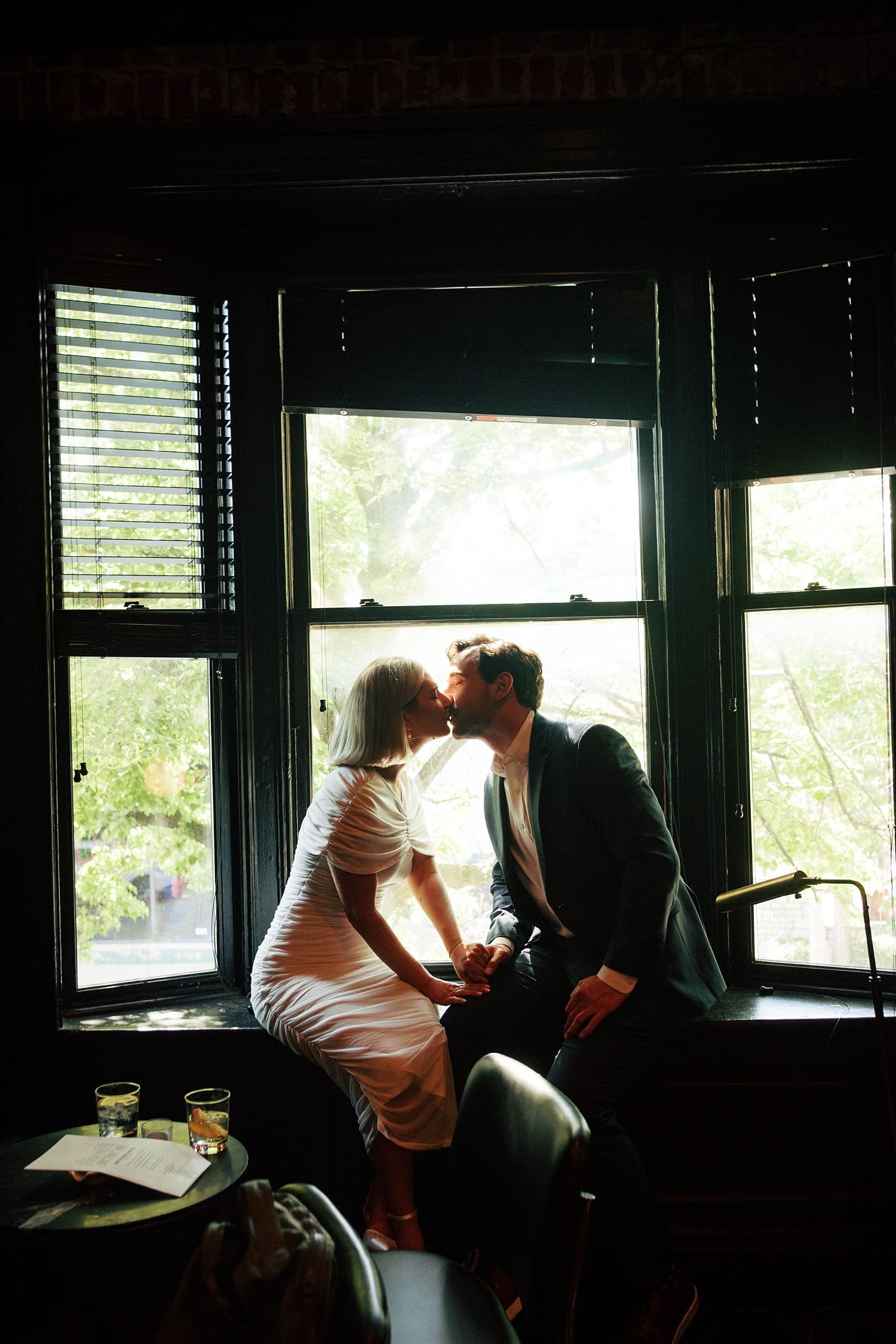 couple kiss in big three pane window at Brennan's in Central West End