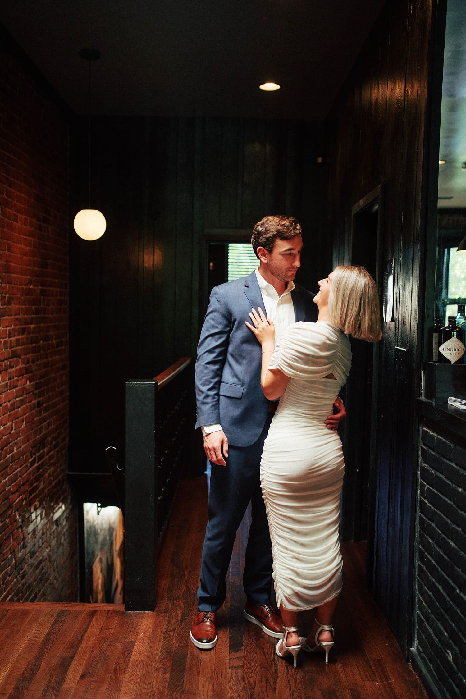 engaged couple embrace at the top of a restaurant staircase by Camille Meers Photography