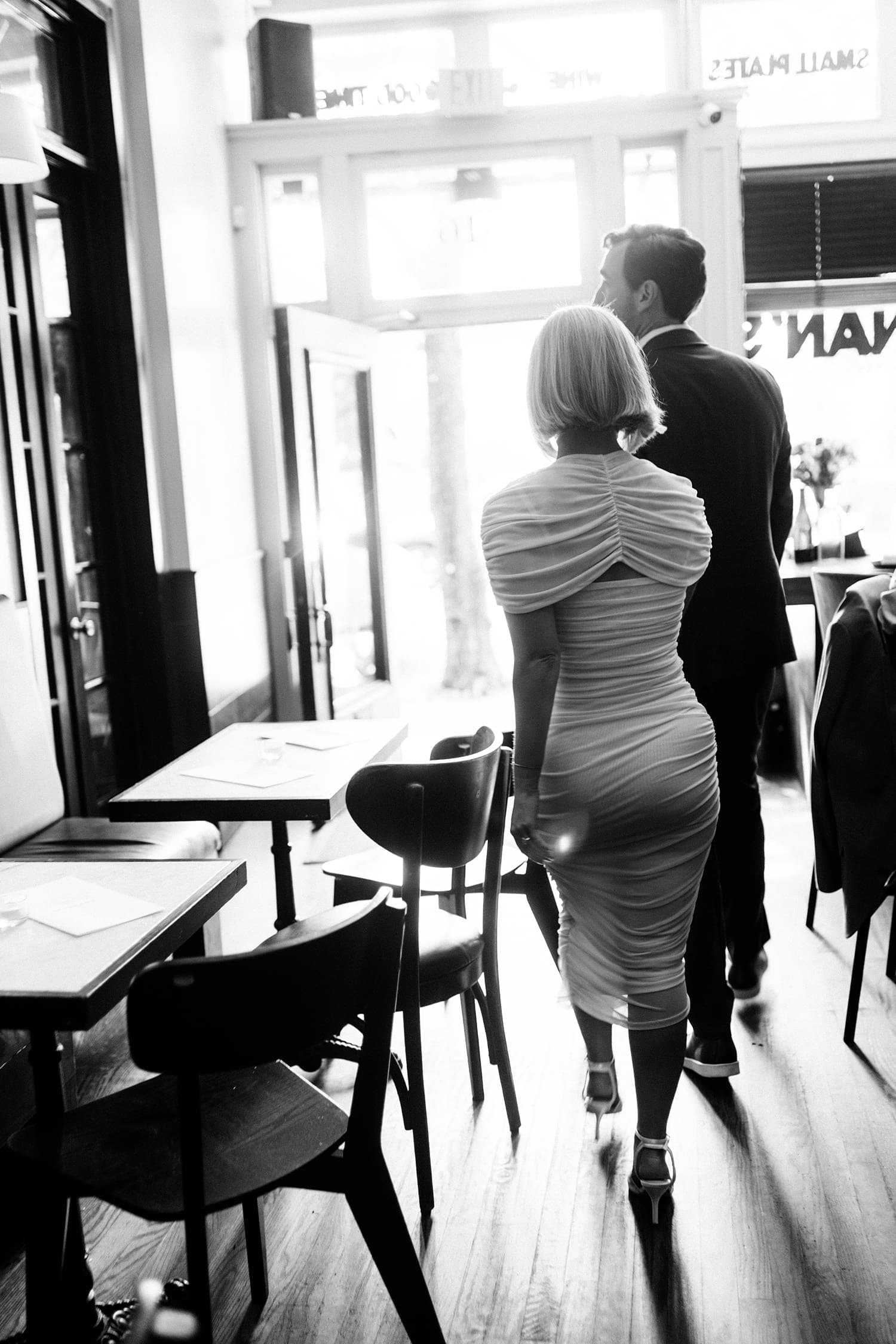 woman in ruched white dress walks past empty tables at Brennan's in Central West End